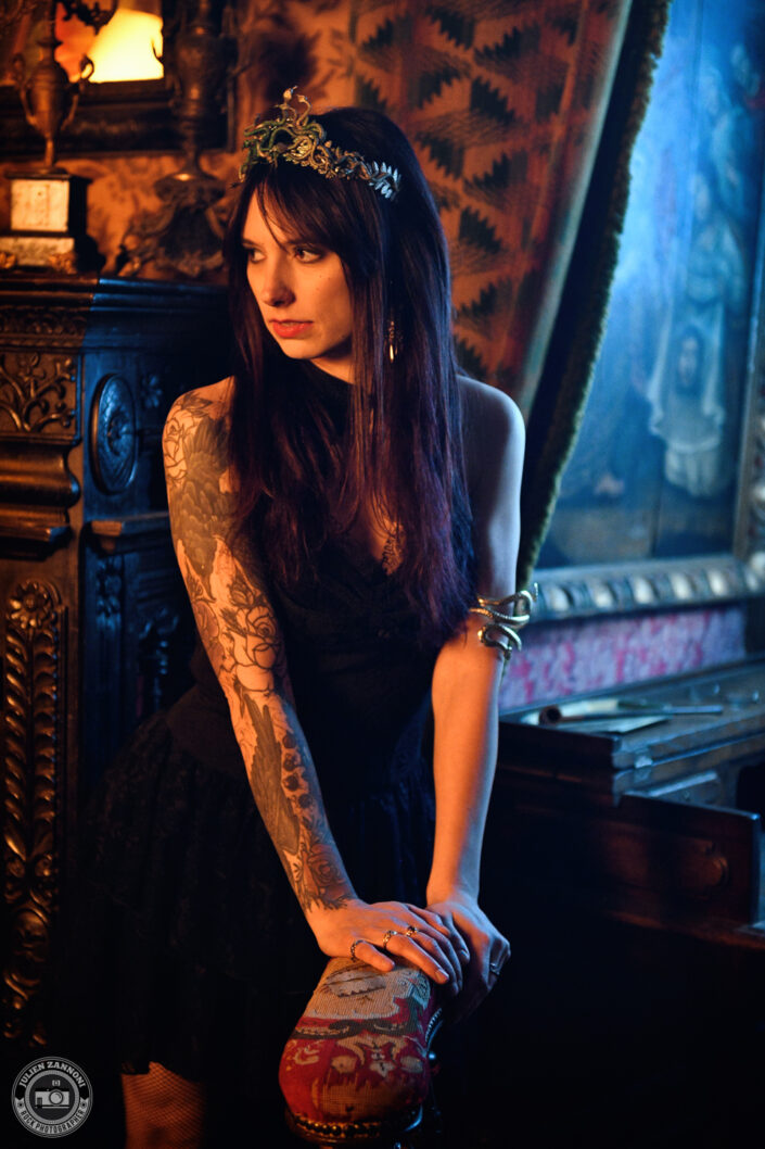 Laurhell en portrait par Julien Zannoni, regard perçant et maquillage sombre, jouant avec les ombres du décor gothique
