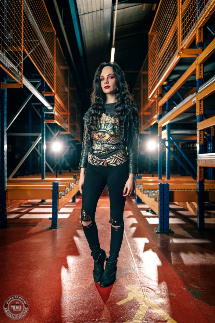 Melany Wild en tenue rock dans un entrepôt industriel, lumière de scène et look Def Leppard, photo par Julien Zannoni