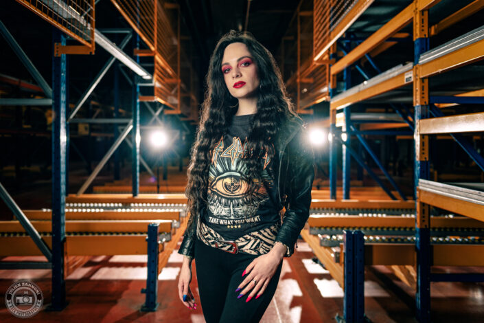 Melany Wild en tenue rock dans un entrepôt industriel, lumière de scène et look Def Leppard, photo par Julien Zannoni