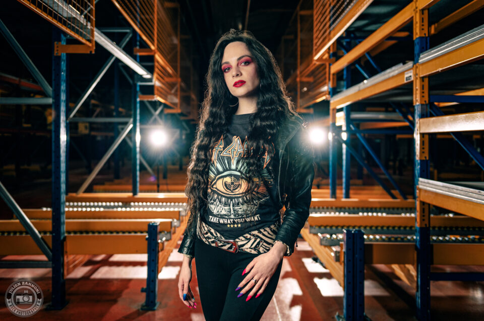 Melany Wild en tenue rock dans un entrepôt industriel, lumière de scène et look Def Leppard, photo par Julien Zannoni